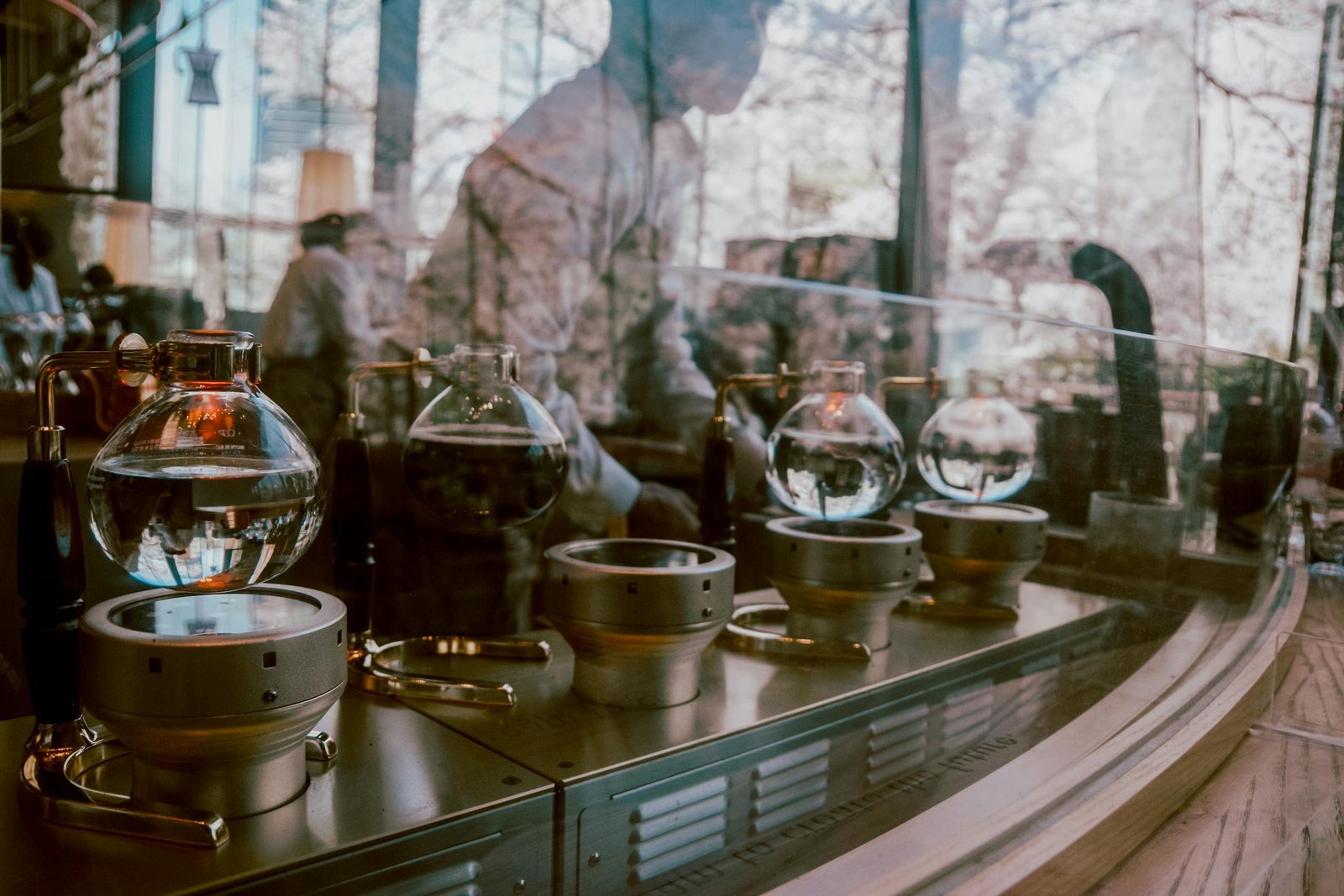 A barista brews coffee using a syphon in a modern cafe, reflecting urban life.
