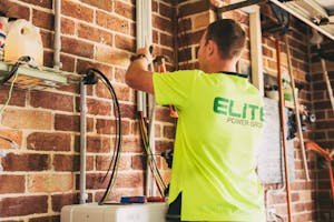 Electrician performing solar battery installation for sustainable energy storage in a home setting.