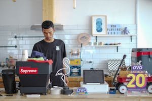 Young barista in Indonesia preparing coffee in a stylish modern café interior.
