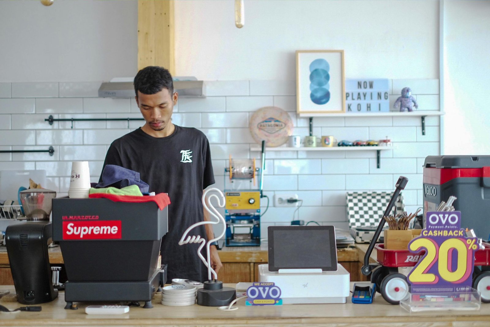 Young barista in Indonesia preparing coffee in a stylish modern café interior.