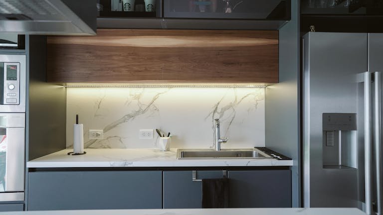 Sleek minimalist kitchen design featuring marble countertop and stainless steel appliances.